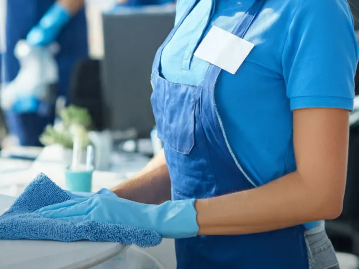 Cleaner wiping down an office desk with a microfibre cloth